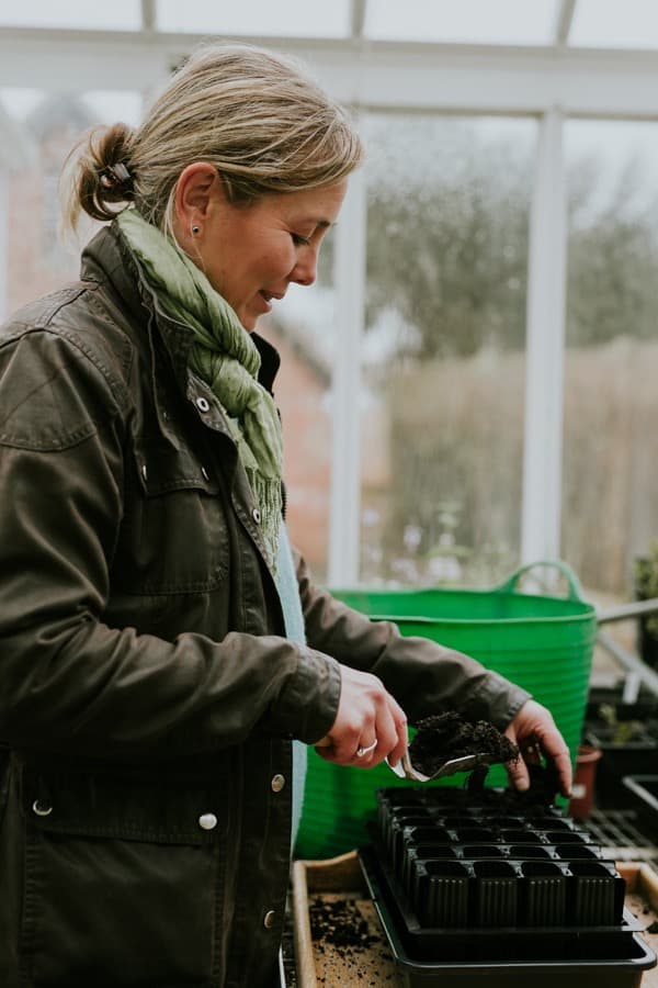 Clare Foster adding compost to a seed tray in her greenhouse