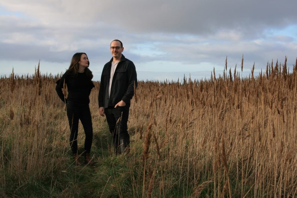 Joe and Laura Carey stood amongst tall grasses in an open field