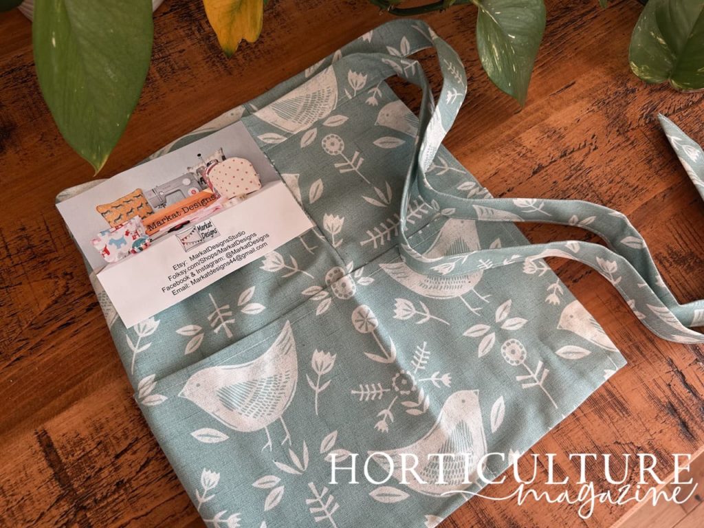 gardening half-apron in a teal colour with a white bird and floral print