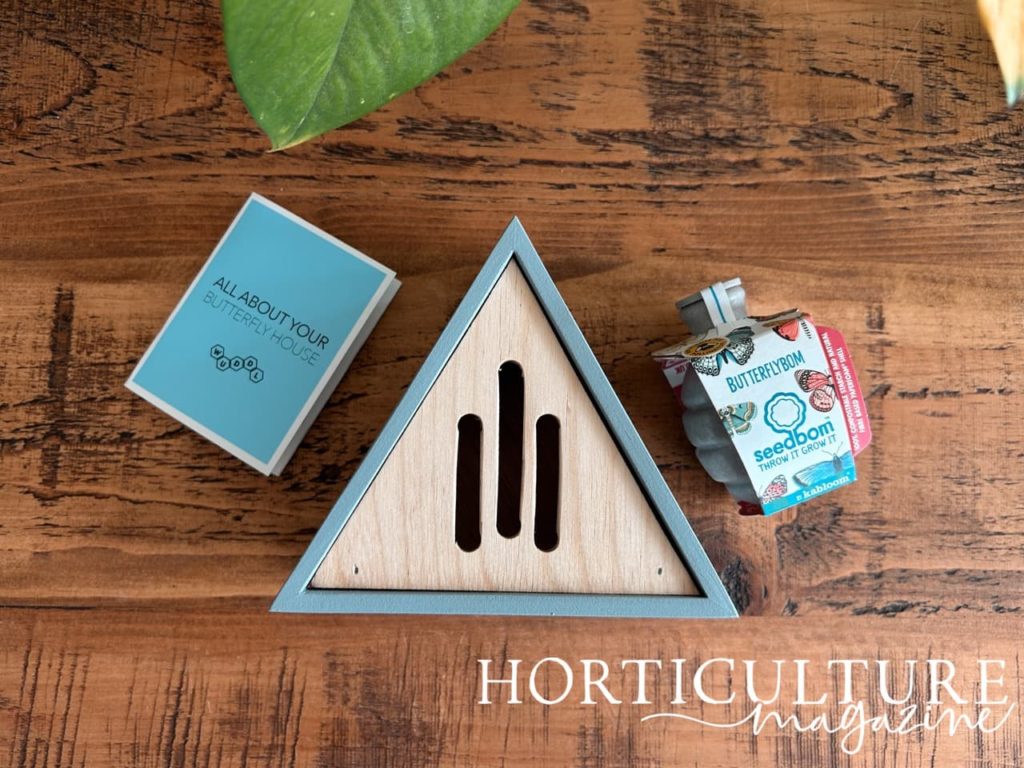 a triangular shaped blue butterfly house next to a seedbom from Kabloom