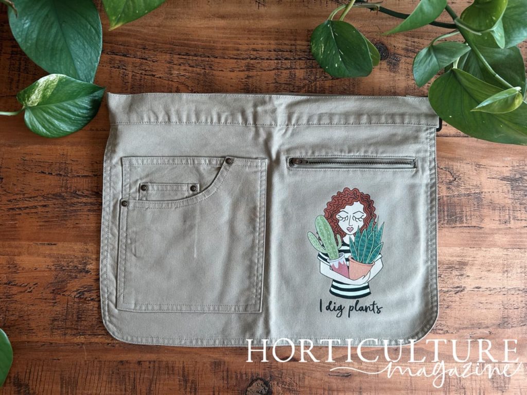 grey half-apron with a large plant lady print on the right hand side and 4 pockets