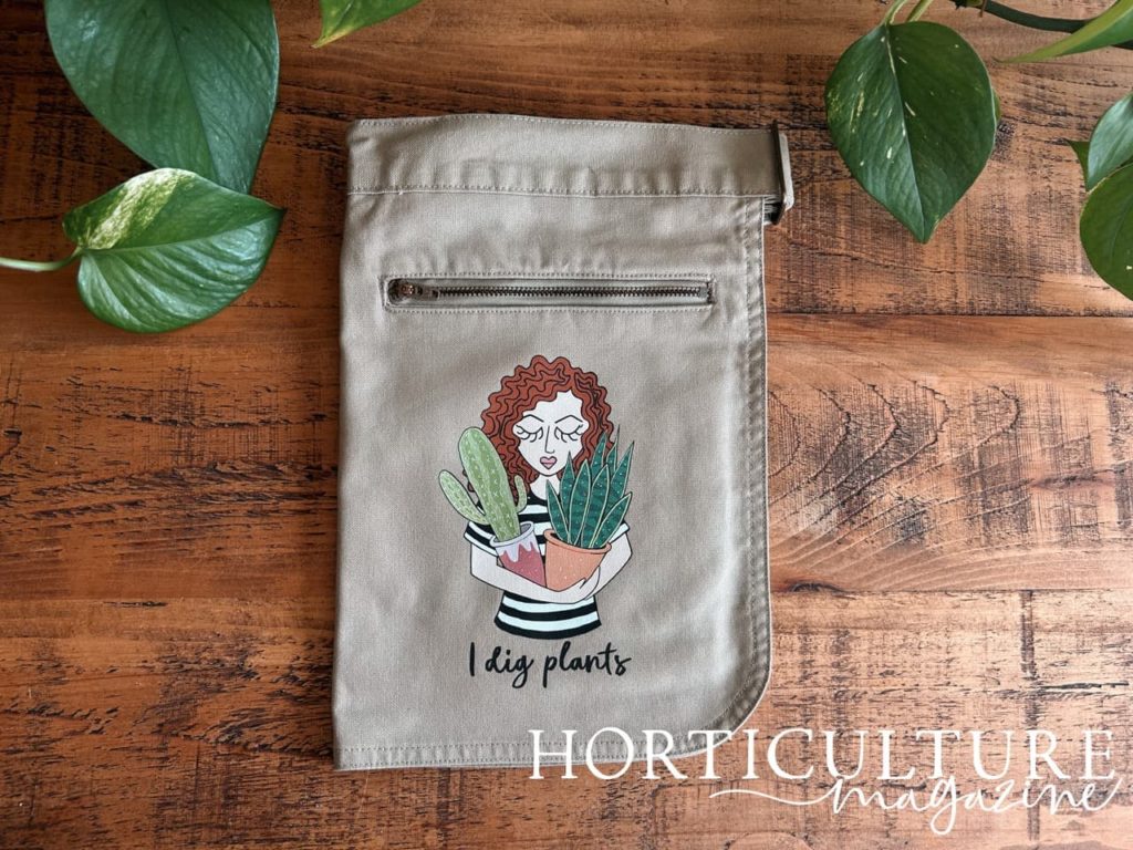 folded apron from syd & co with an illustration of a woman holding plants printed onto it