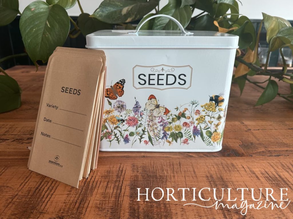 large seed tin with a floral print on the front and some seed envelopes resting against it