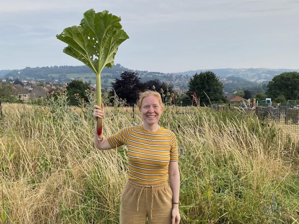 Gemma holding up a harvested rhubarb crop from her allotment