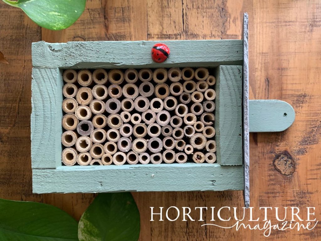 Insect hotel lying on its side painted blue with a decorative ladybug