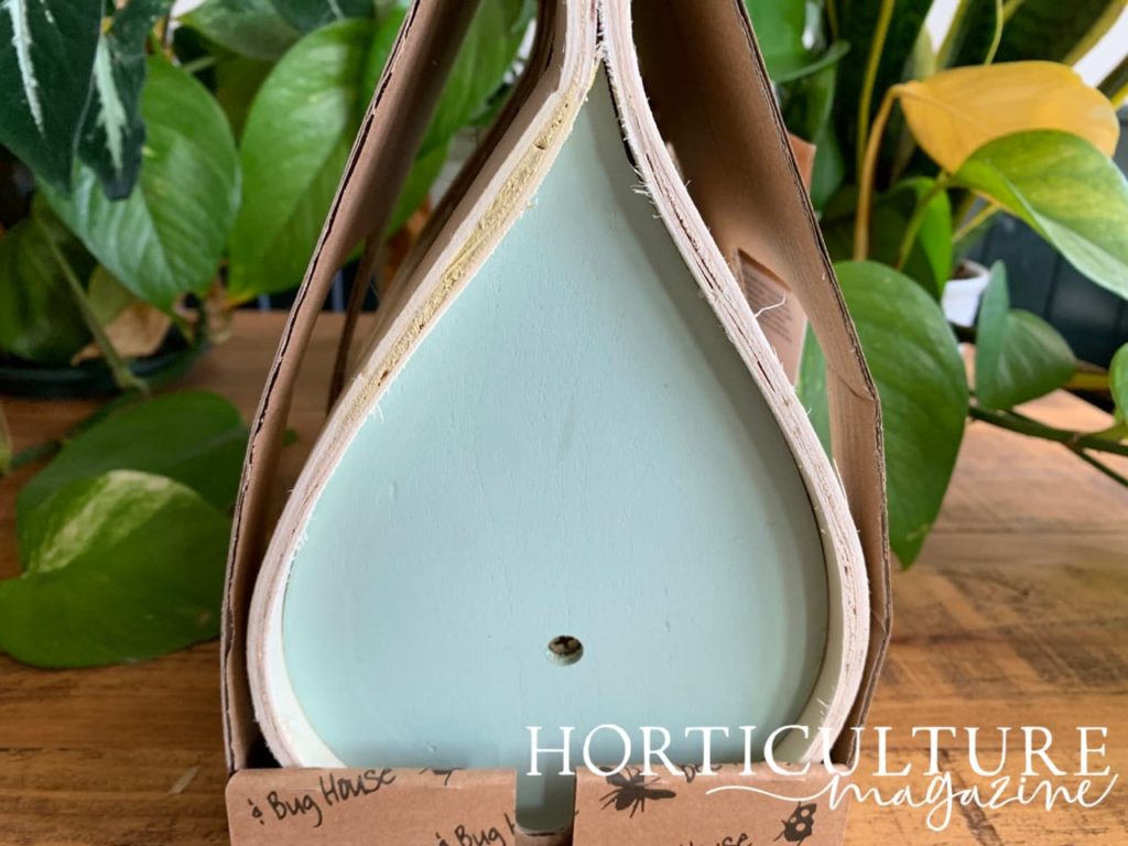 the painted blue back of an insect hotel shaped like a teardrop