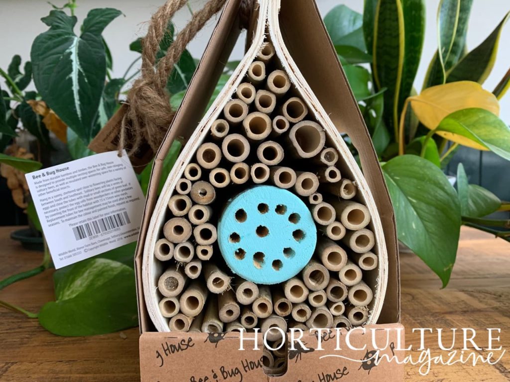 a dewdrop-shaped bee and bug hotel with a blue centre on a table indoors