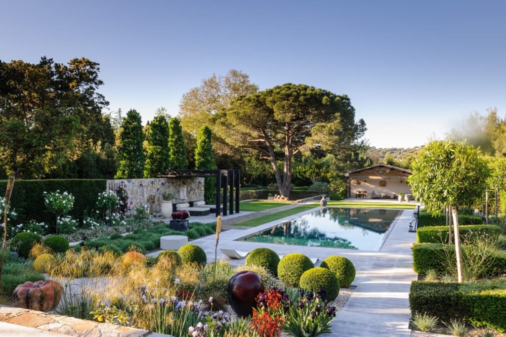 a large outdoor pool surrounded by topiary shrubs and formal planting