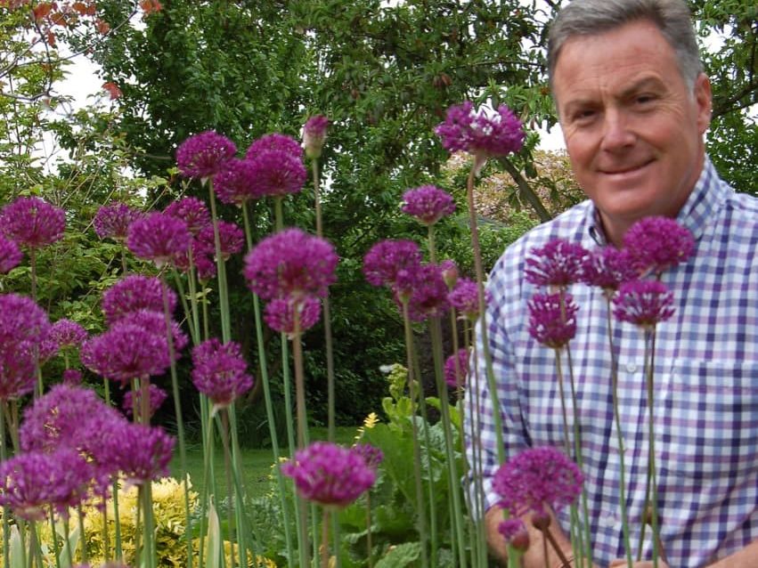 Martin Fish posing next to some purple flowering alliums 