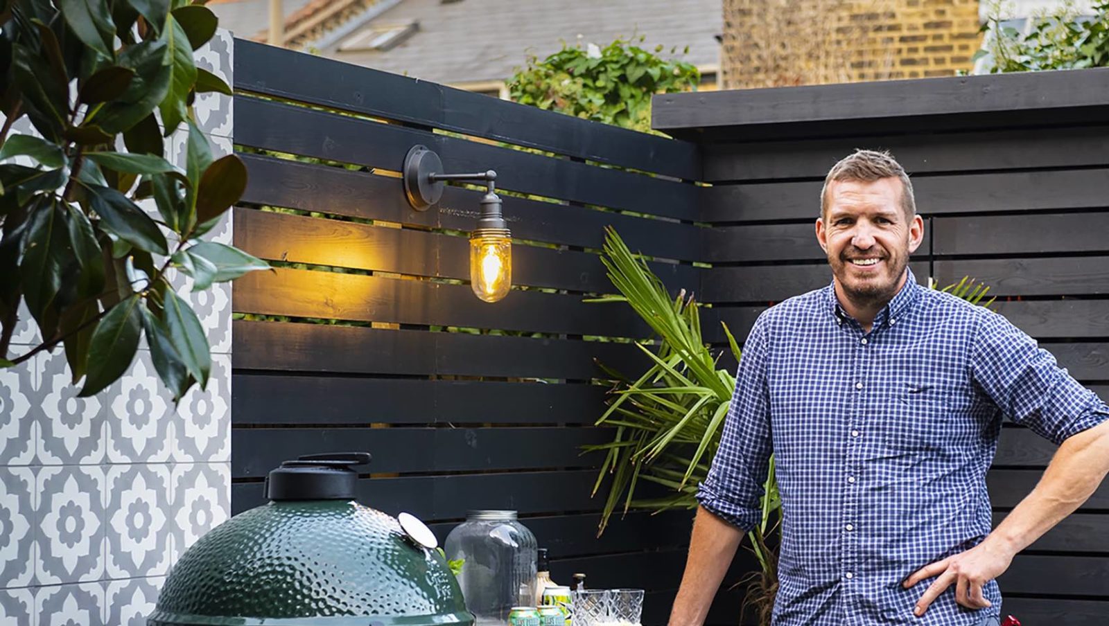 Chris Harrington posing next to an outdoor kitchen area he has designed
