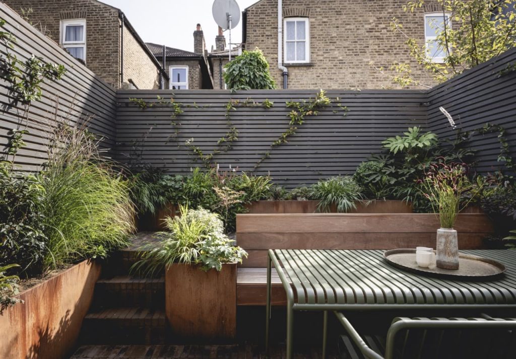 Rodwell garden with wooden decking and chairs and foliage plants growing in borders