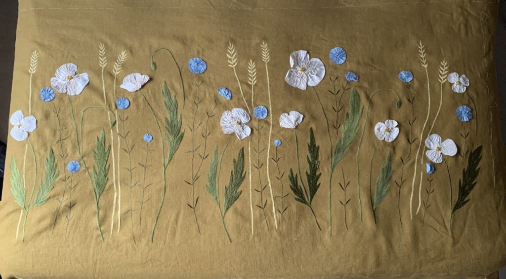 white and blue flowers stitched into a yellow cloth