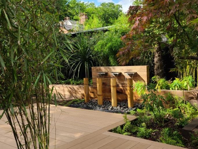 bamboo in front of wooden decking and a water feature in an oasis garden designed by DK Garden Design
