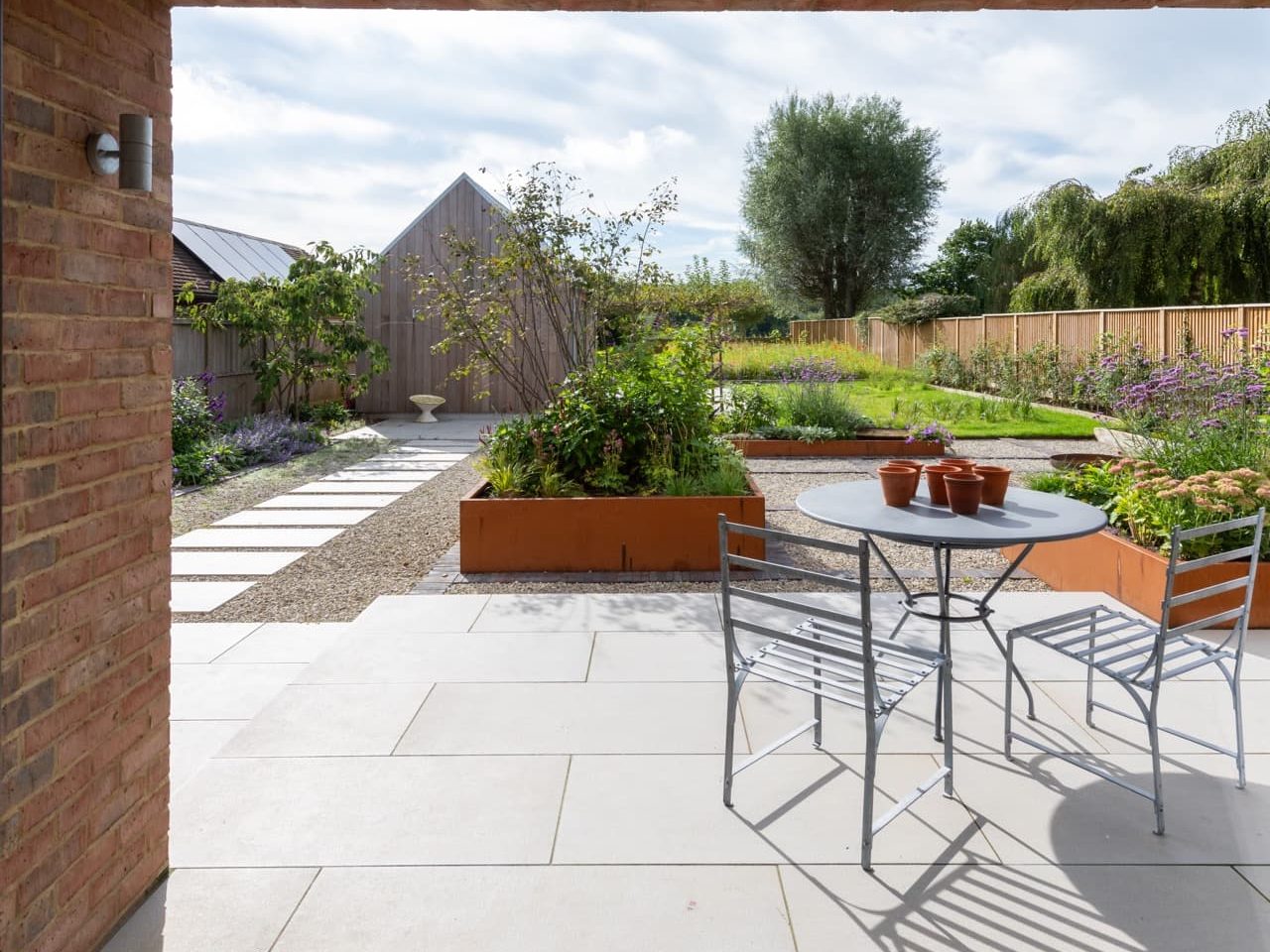 garden patio area featuring raised beds and deck chairs designed by Lottie Delamain