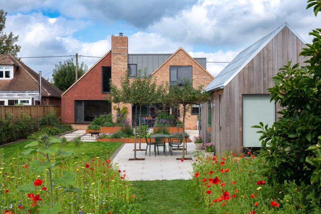a large modern house with a big garden designed by Lottie - featuring lots of poppies and a beautiful patio area