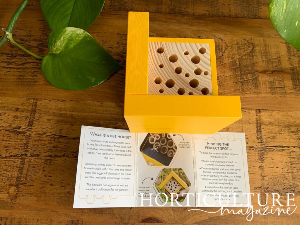 instruction manual next to a bee house in a bright yellow shade