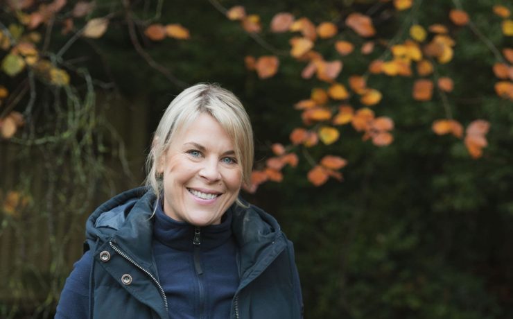 Lisa Norton headshot taken outside with autumn leaves in the background