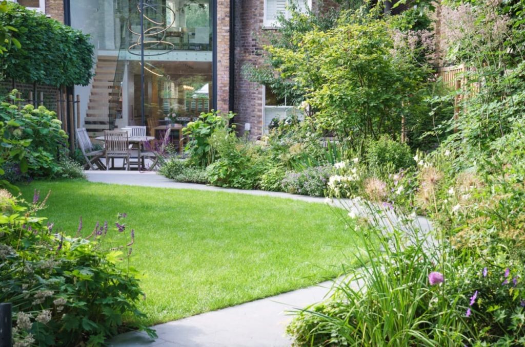 mowed lawn surrounded by a path and garden borders in front of a house