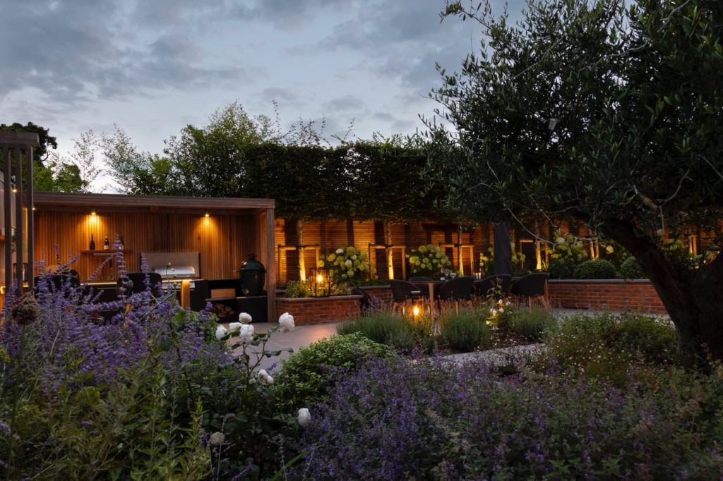 outdoor area with BBQ space designed by Raine lit up in the evening