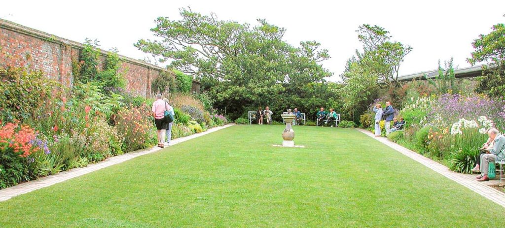 people sat on the benches around the mowed lawn of the sundial garden