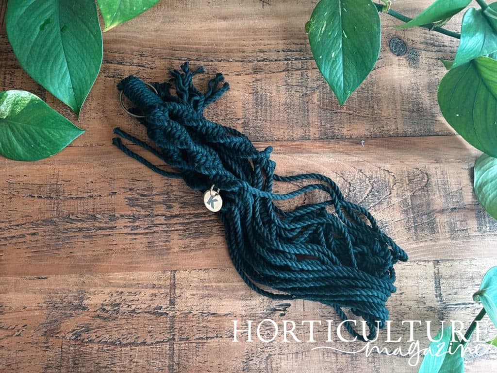 black macrame hanger lying on a wooden table