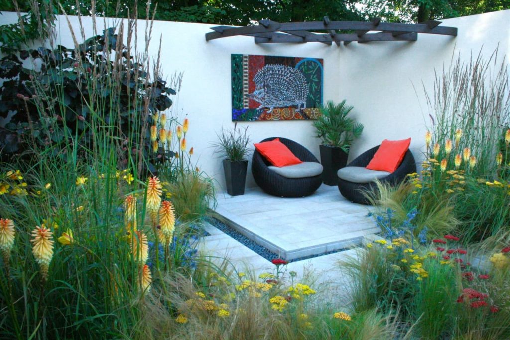 hedgehog garden designed by Tracy with bright yellow Kniphofia flowers in the borders that surround the patio area