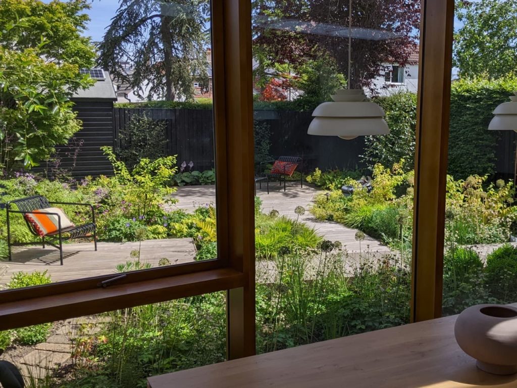 a shot of a garden with a patio woven throughout taken from inside a conservatory