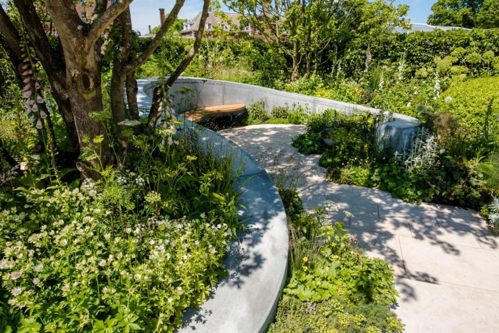 RHS show garden by Kate Savill with raised garden borders full of green-leaved plants and small trees