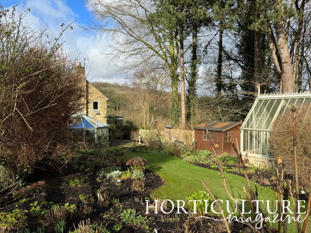 formal garden beds surrounding a mowed lawn next to a green house at Chevin Brae