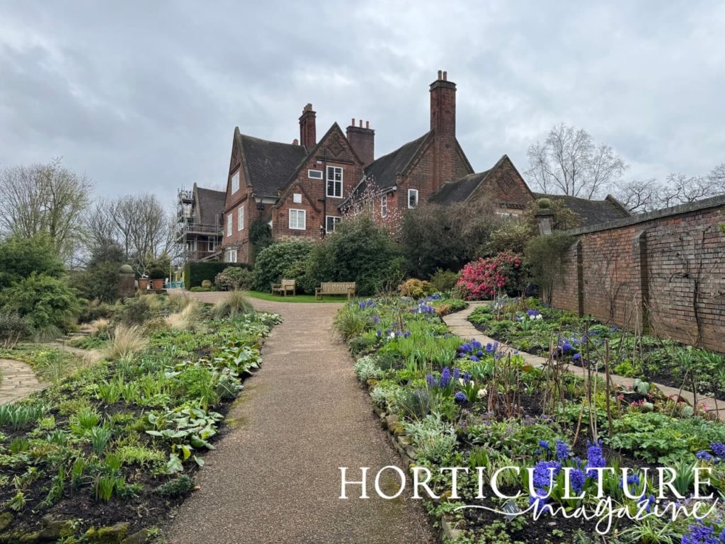 the house at Winterbourne with a path leading up to it surrounded by flowering herbaceous borders