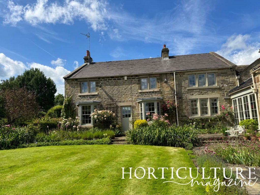 the house at Swindon House Farm with climbing plants up it and a large cut lawn in front